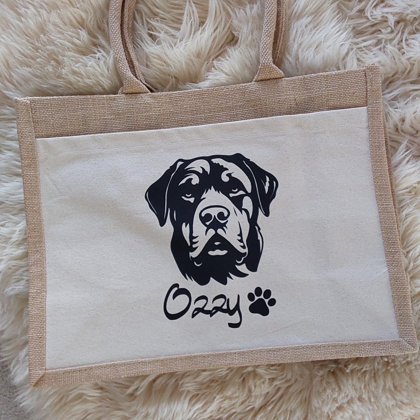 Canvas tote bag with black dog design and paw print on a fluffy white surface